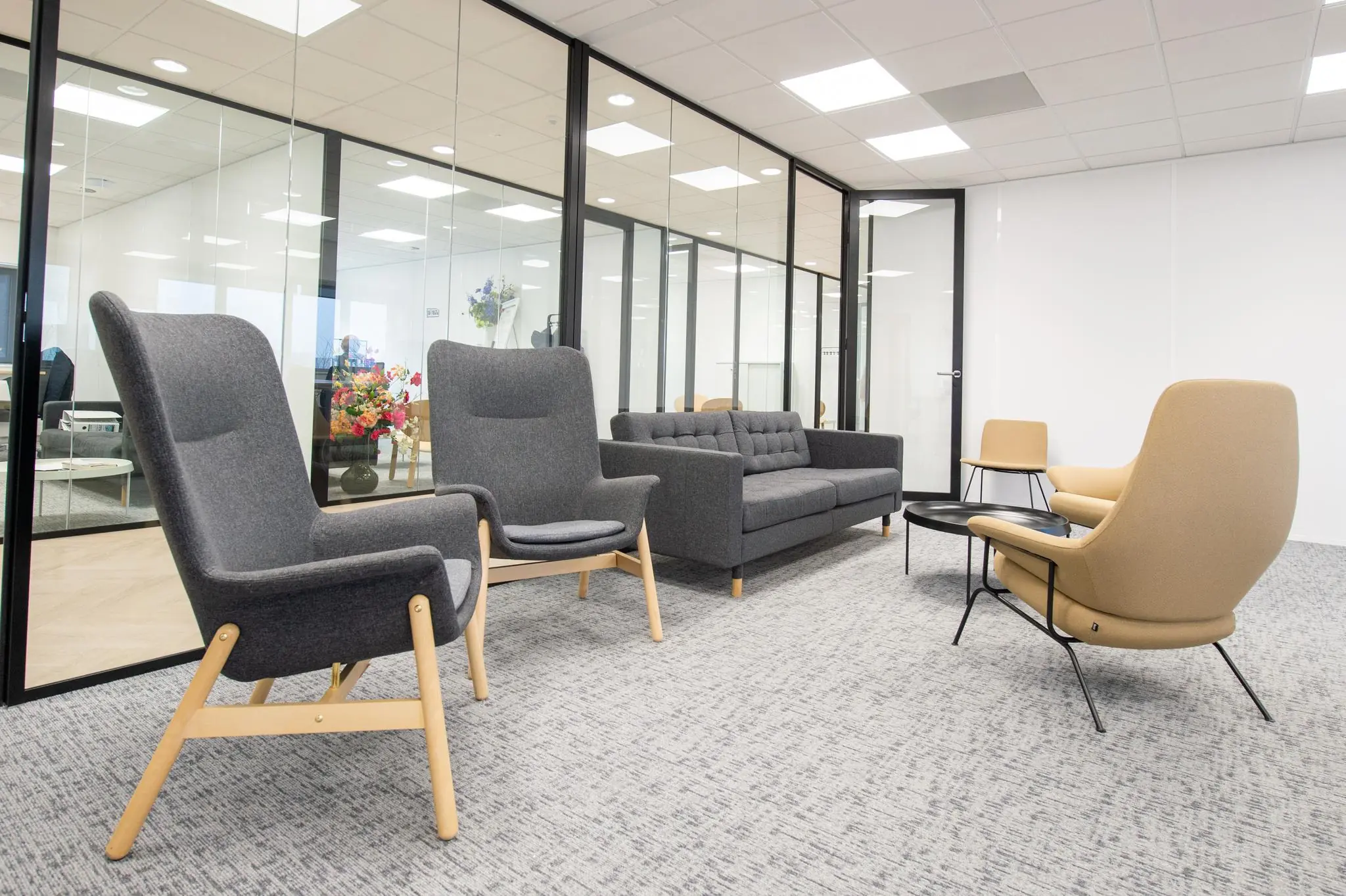 Moderne wachtruimte in Rivium Quadrant met grijze en beige designstoelen, glazen wanden en een strakke, lichte inrichting.